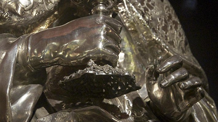 Metal sculpture of hands holding hilt of sword