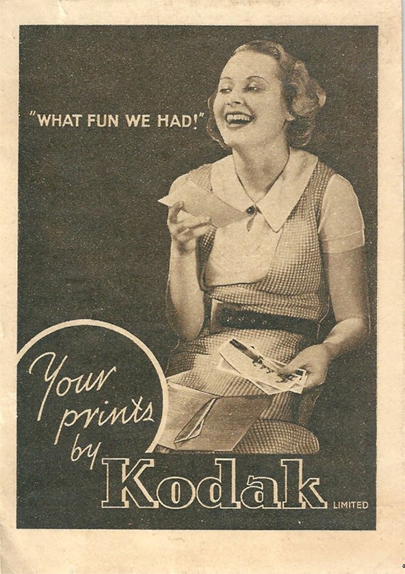 An advertisement poster for the camera brand Kodak in faded sepia colours, showing a laughing woman holding several photographs in her hands. The writing next to her in quotations says: "What fun we had!" and at the text at the bottom of the page says:"Your prints by Kodak Limiited".
