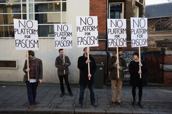 Photograph of three young men and a young woman holding up signs that say "NO PLATFORM FOR FASCISM"