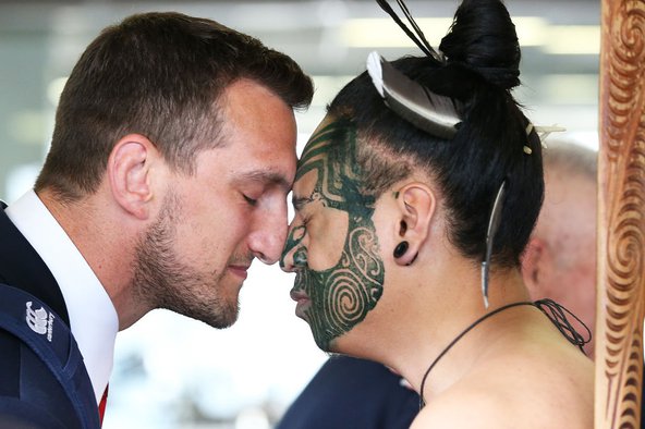 A close-up of Welsh rugby player Sam Warburton receiving a &#x27;hongi&#x27; from a Maori chief. The two men are pressing their noses together with their eyes closed.