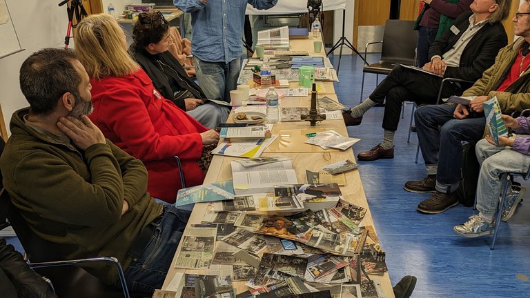 People sat around a table at a workshop with pictures and documents on the table