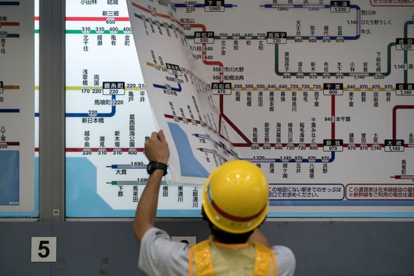 An employee wearing a yellow safety helmet replaces a map showing all train routes and fares at an East Japan Railway Co. train station on October 1, 2019 in Tokyo, Japan. Japan